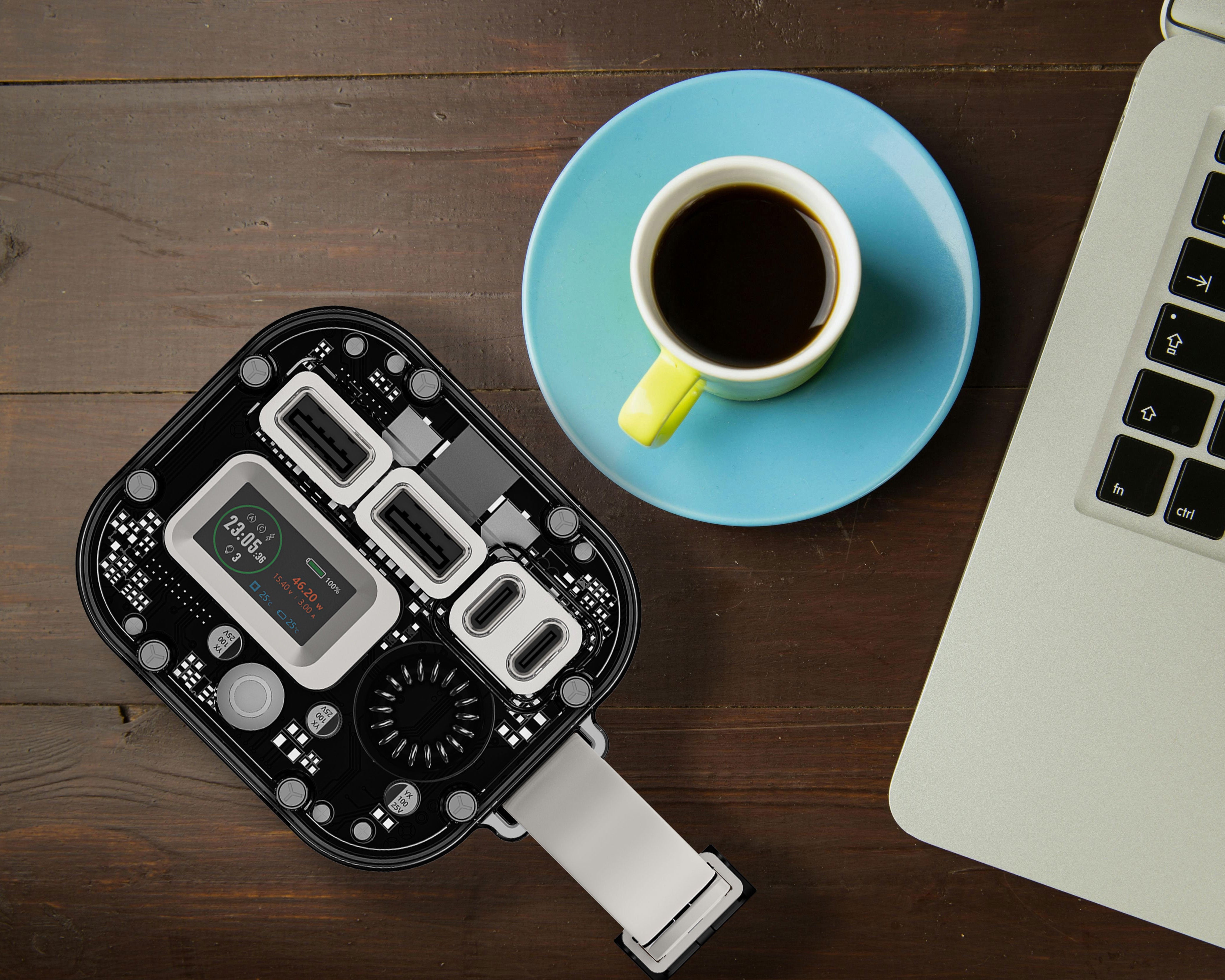 Gletscher Camper Pico power hub with transparent casing and digital display, placed beside coffee cup and laptop on wooden desk