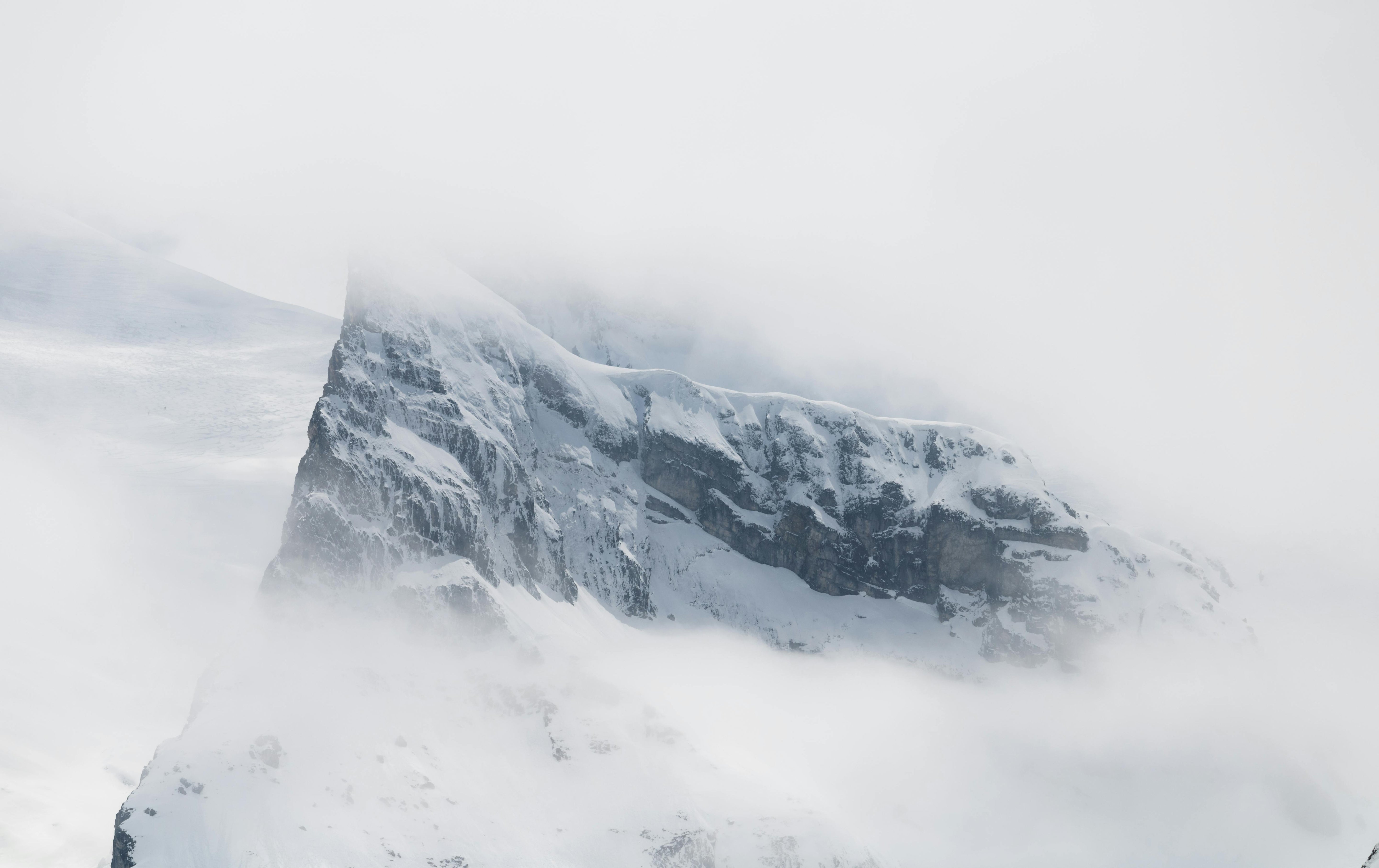 Snow-covered mountain peak emerging through clouds and mist, symbolizing the strength, clarity, and resilience behind Gletscher Energy’s brand identity.