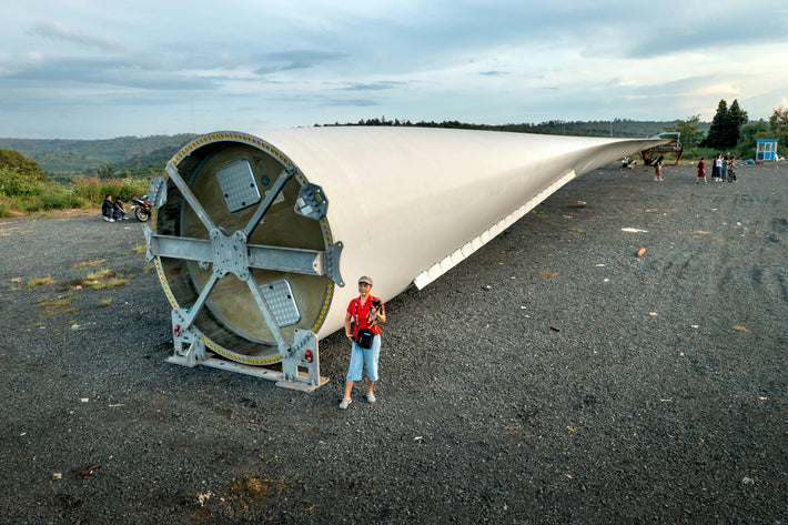 Massive wind turbine blade staged for installation with people for scale, showcasing Gletscher Energy wind infrastructure
